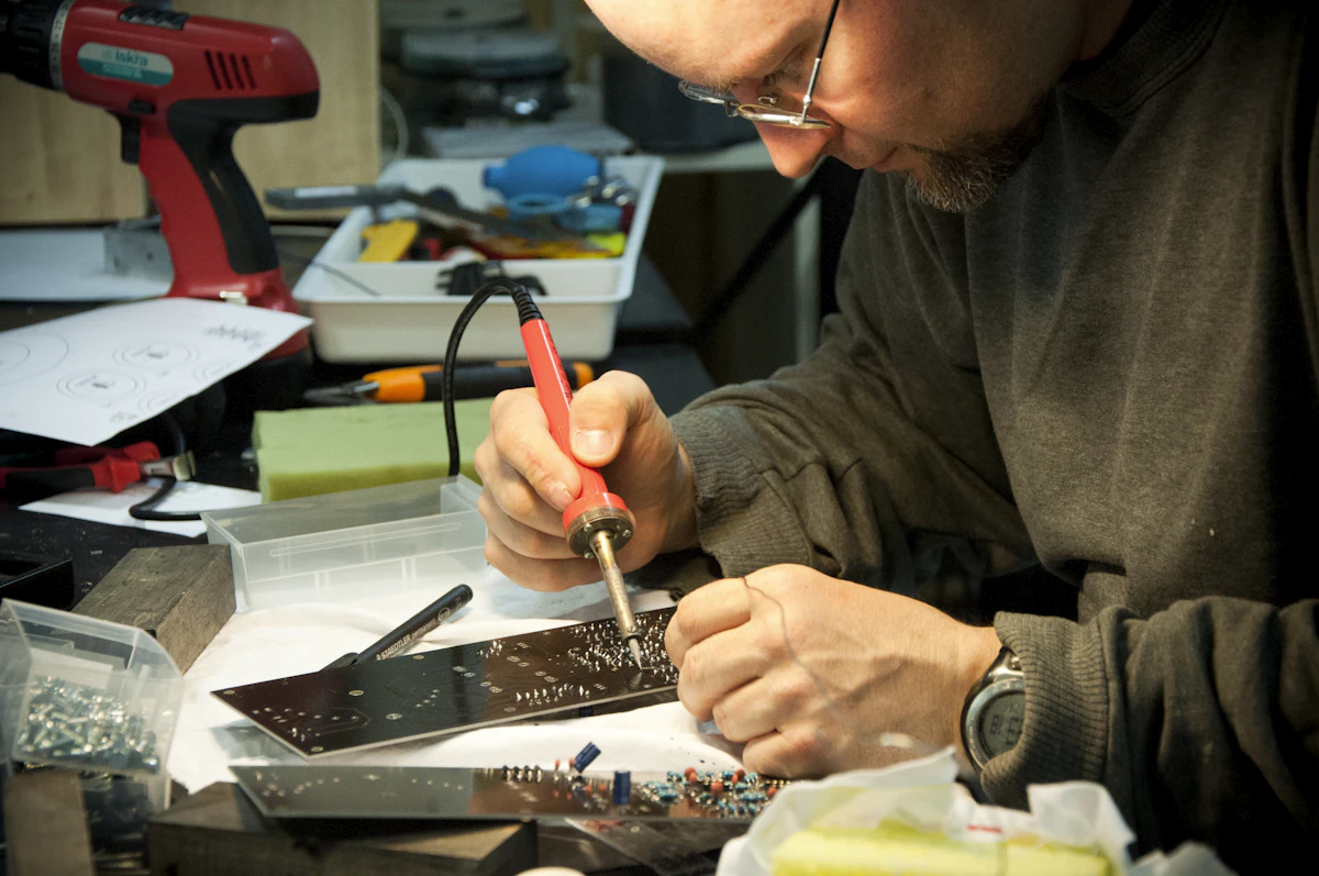 Technician repairing an LED TV circuit board with a soldering iron